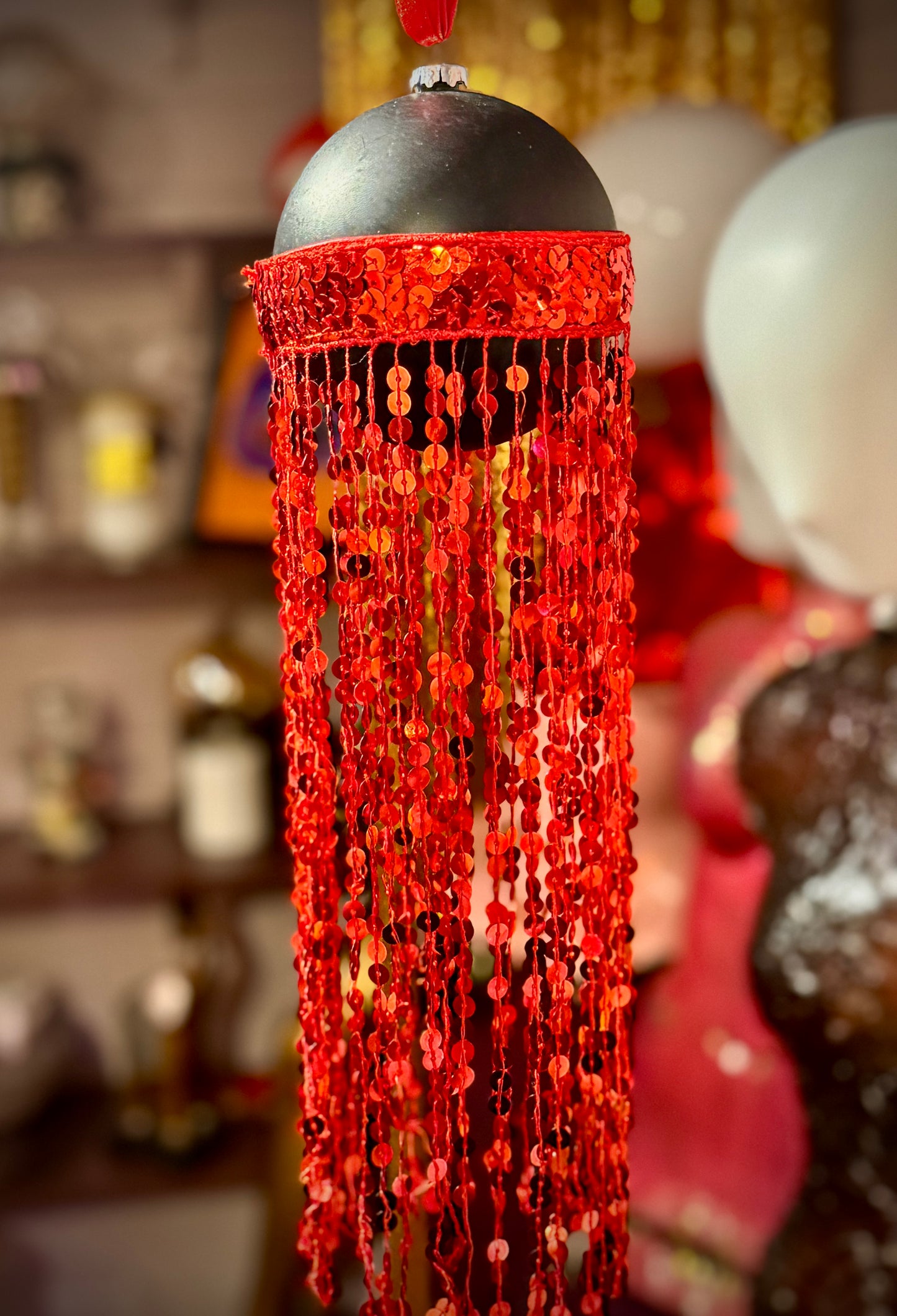 Svart julekule med røde lange paljettfrynser