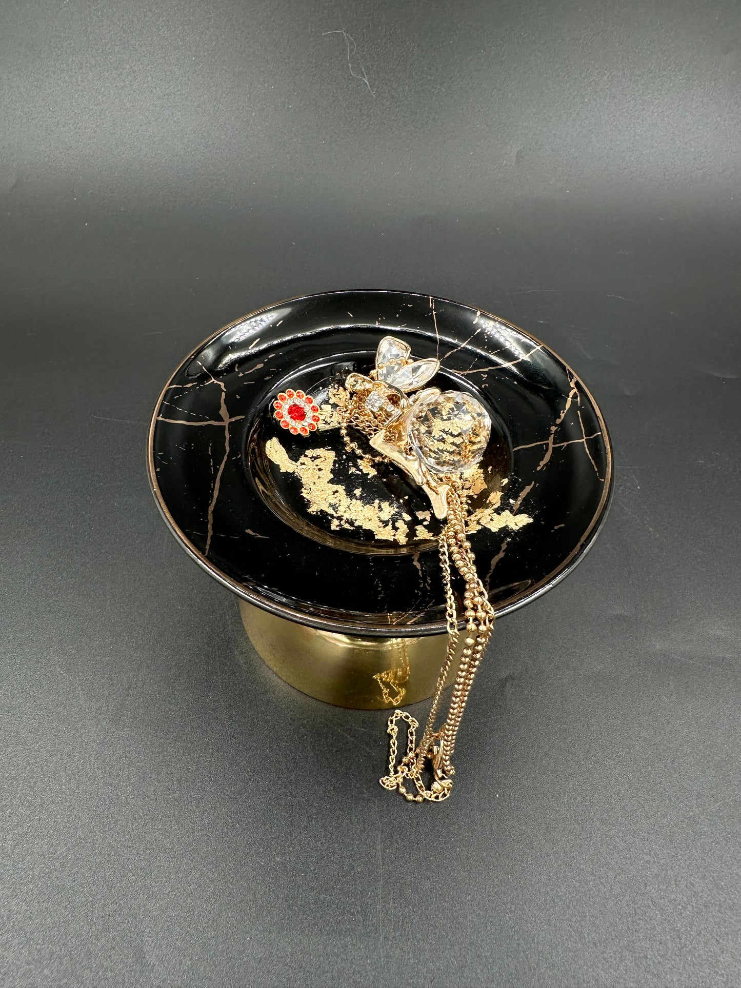 Vulvakunst med gullfot og svart fat med rød diamantblomst
