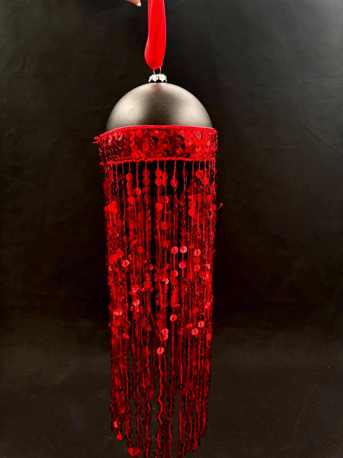 Svart julekule med røde lange paljettfrynser