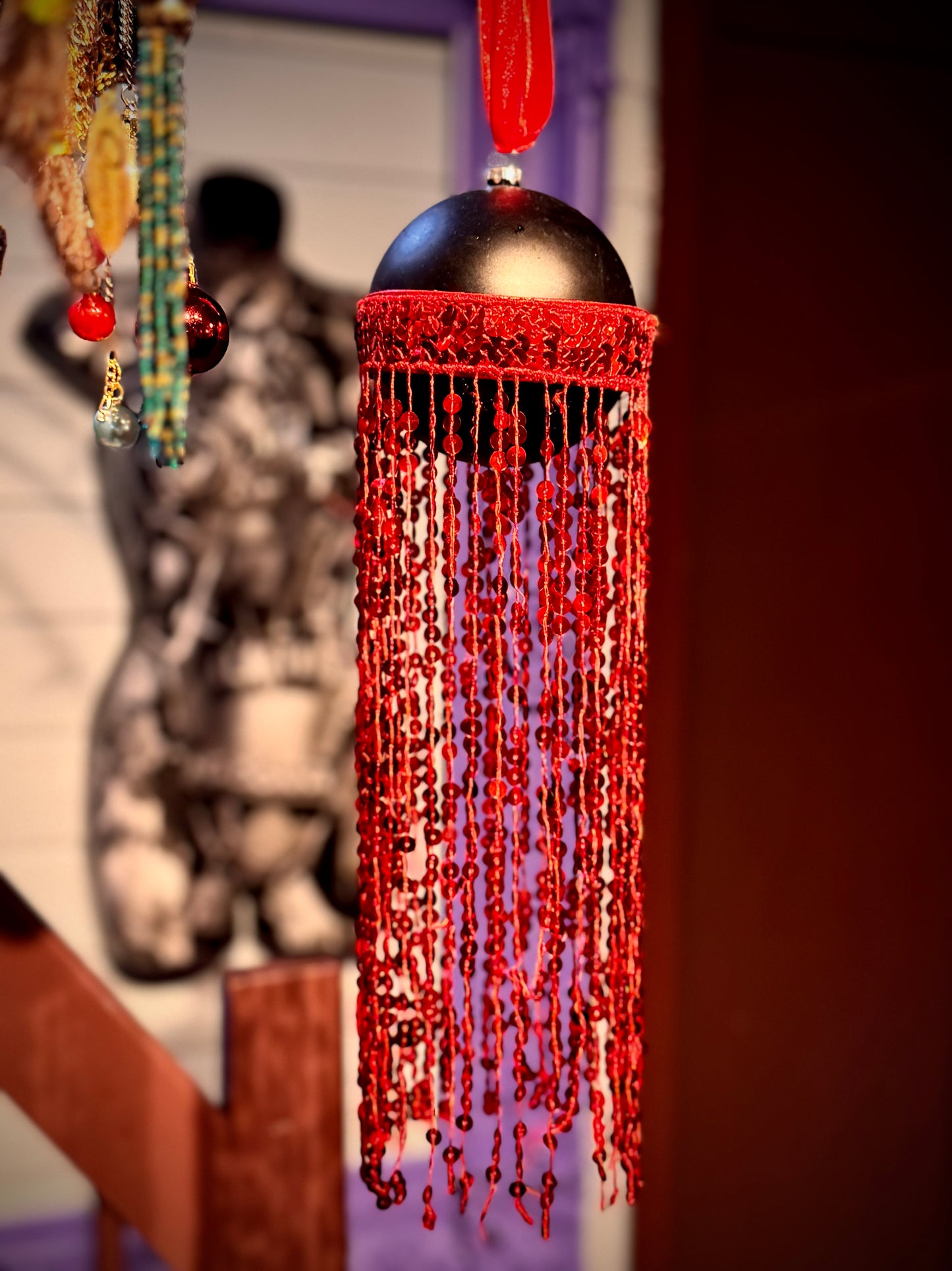 Svart julekule med røde lange paljettfrynser